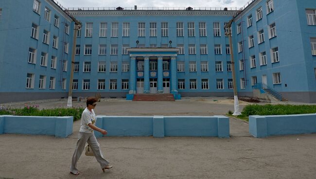 Прохожая у здания школы в городе Луганске