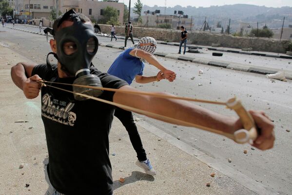 Палестинский демонстрант использует рогатку во время столкновений с Израильскими военными в секторе Газа