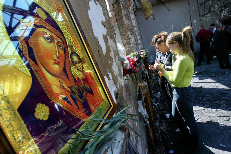 Школьницы зажигают свечи в спортзале школы в Беслане, где находились заложники 9 сентября 2004