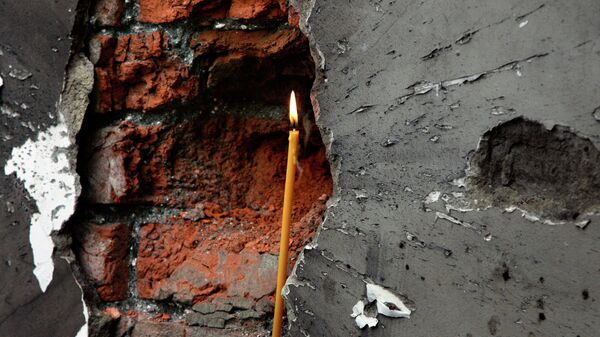 Свеча в воронке от взрыва стены школы в Беслане 10 сентября 2004. Архивное фото