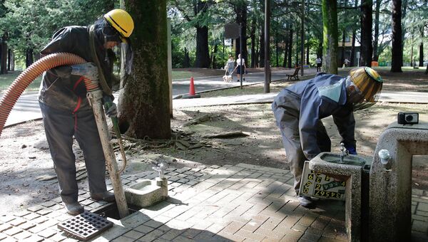 Работники чистят канализацию в парке Ёёги в Токио