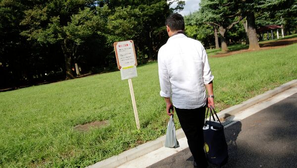 Посетитель читает предупреждающий плакат о москитах в парке Ёёги в Токио