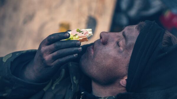 Участник акции оппозиции ест бутерброд на баррикаде на улице Грушевского в Киеве