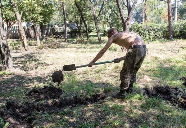 Пленный украинский военный роет могилу для погибших сослуживцев в результате боев в городе Шахтерск под Донецком