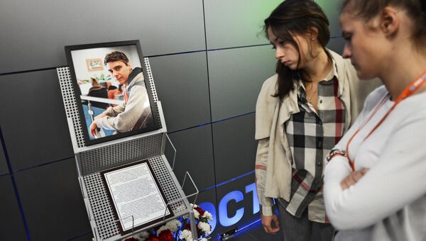 Коллеги скорбят у фотографии погибшего на Украине фотокорреспондента Андрея Стенина в здании МИА Россия сегодня.