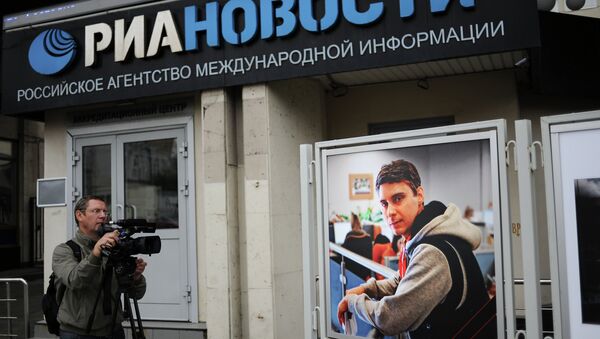 Видеооператор у фотографии погибшего на Украине фотокорреспондента Андрея Стенина у здания МИА Россия сегодня