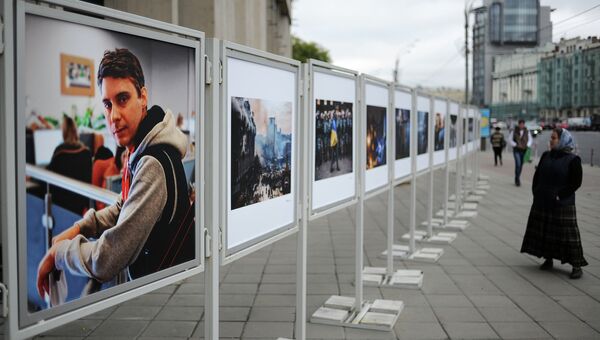 Жительница Москвы рассматривает работы погибшего на Украине фотокорреспондента Андрея Стенина у здания МИА Россия сегодня