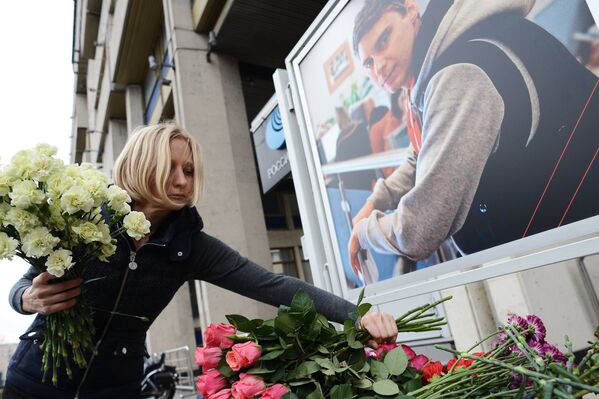 Коллега возлагает цветы в память о погибшем на Украине фотокорреспонденте Андрее Стенине у здания МИА Россия сегодня