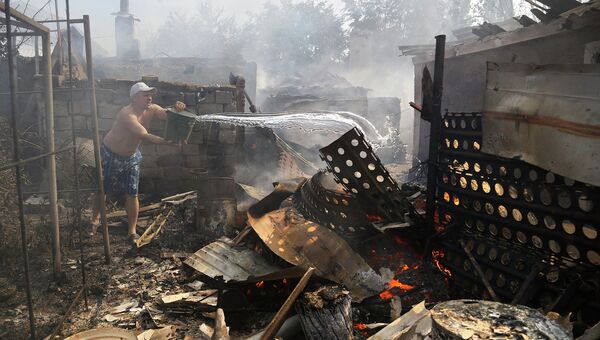 Житель Донецка тушит пожар в своем доме после обстрела. Архивное фото