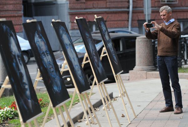 Мужчина фотографирует портреты, нарисованные московскими художниками на акции в память журналистов, погибших в горячих точках