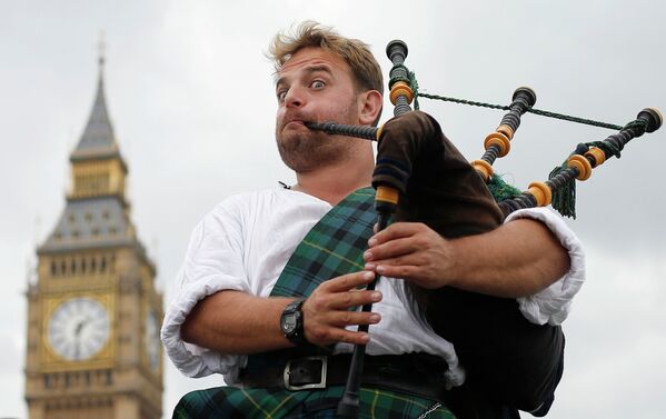 Волынщик и уличный музыкант Дэвид Уитни Абердине играет на волынке в центре Лондона