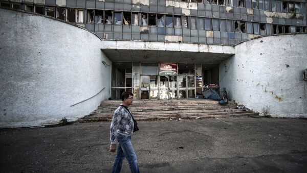 Житель Луганска проходит мимо здания, поврежденного артобстрелом. Архивное фото