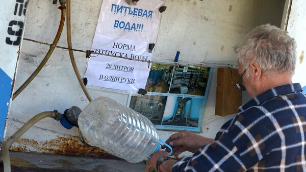 Житель Луганска набирает в канистры питьевую воду. Архивное фото