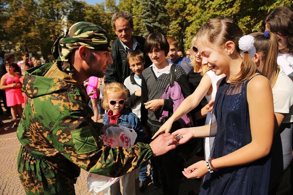 Сепаратистская солдат раздает конфеты детям во время празднования дня города