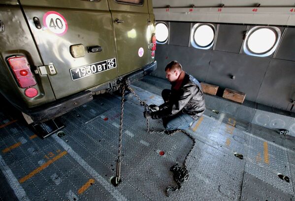 Военнослужащий закрепляет технику, погруженную в транспортный самолет АН-12БК