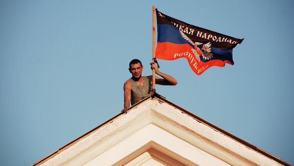 Ополченец Донецкой народной республики (ДНР) устанавливает флаг ДНР на здании мэрии города Комсомольское Донецкой области. Архивное фото