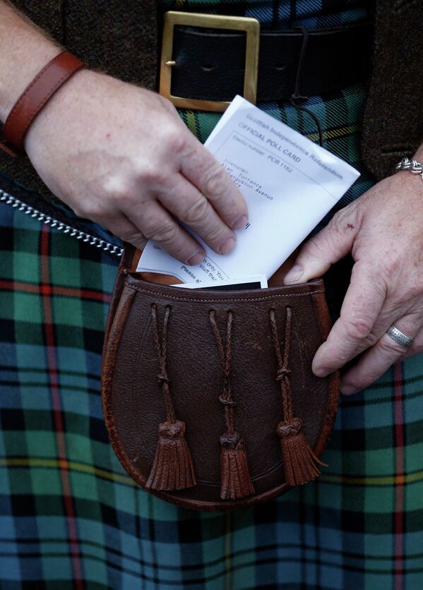 Избиратель достает карточку для голосования на референдуме в Шотландии