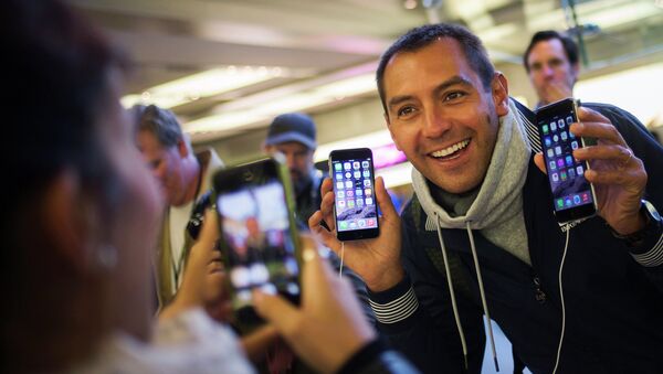 Мужчина с телефонами iPhone 6 и iPhone 6 Plus в первый день продаж в магазине Apple в Нью-Йорке