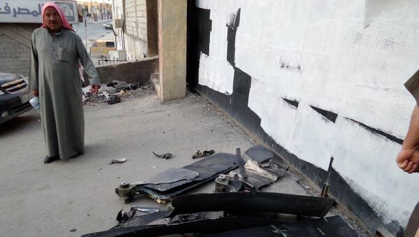 Житель города Раккаа осматривает упавший беспилотник армии США
