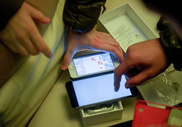 Посетитель московского магазина сотовой связи знакомится с функциями новых смартфонов Apple iPhone 6 и iPhone 6 plus