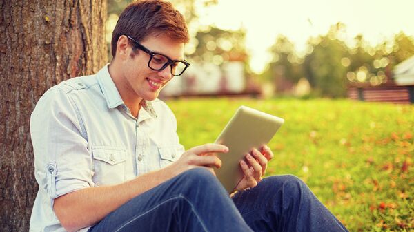 Человек в очках с планшетом в парке под деревом