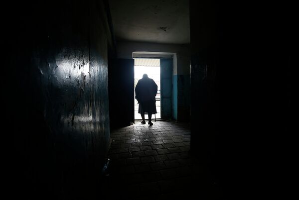 Пожилая женщина покидает здание после обстрела Донецка