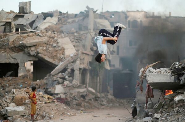 Молодой человек занимается паркуром на разрушенной улице в Секторе Газа