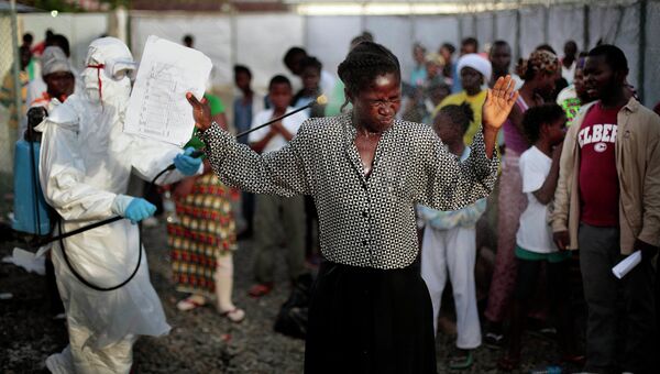 Женщину с выпиской из лечебного центра опрыскивают с целью дезинфекции от лихорадки Эбола, Монровия. 30 сентября 2014