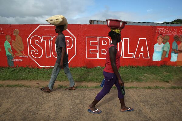 Жители Монровии проходят мимо стены с описанием симптомов лихорадки Эбола. Либерия, 2 октября 2014