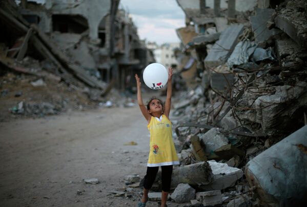 Палестинская девочка играет с воздушным шариком рядом с ее разрушенным домом