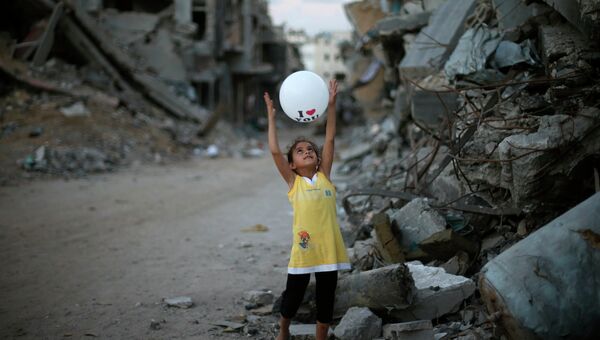 Палестинская девочка играет с воздушным шариком рядом с ее разрушенным домом. Архивное фото