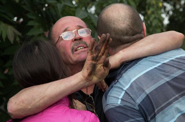 Мужчина обнимает своих родственников после обстрела в Донецке