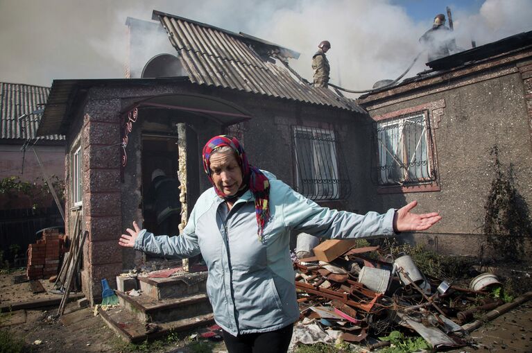 Жительница Донецка рядом со своим домом после артобстрела