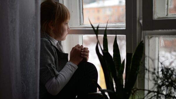 Девочка сидит у окна в детском доме. Архивное фото