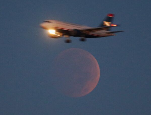 Самолет заходит на посадку в национальном аэропорту имени Рональда Рейгана во время полного лунного затмения в Вашингтоне 8 октября 2014