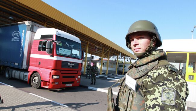 Украинский пограничник стоит у грузовика с гуманитарной помощью из Германии на пограничном пункте в западной Украине. 7 октября 2014