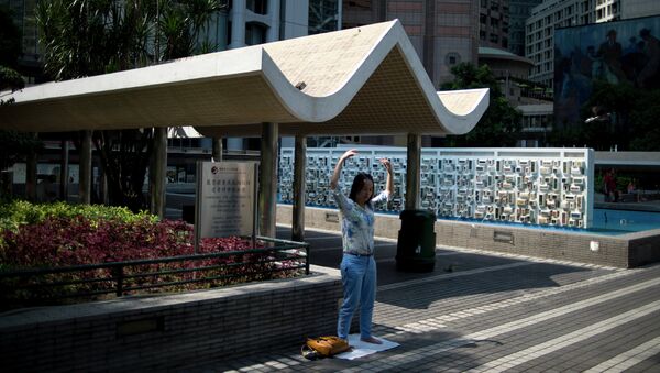 Женщина занимается гинастикой на одной из улиц района Central в Гонконге