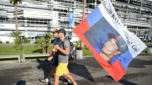 Зрители несут флаг с портретом гонщика команды Торо Россо Даниила Квята