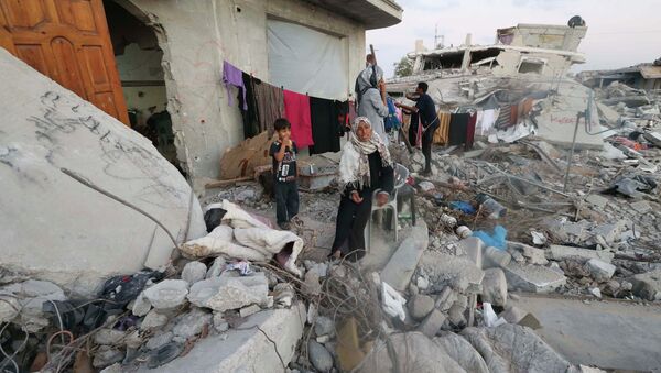 Палестинская женщина у дома в Секторе Газа, разрушенного во время обстрела со стороны Израиля