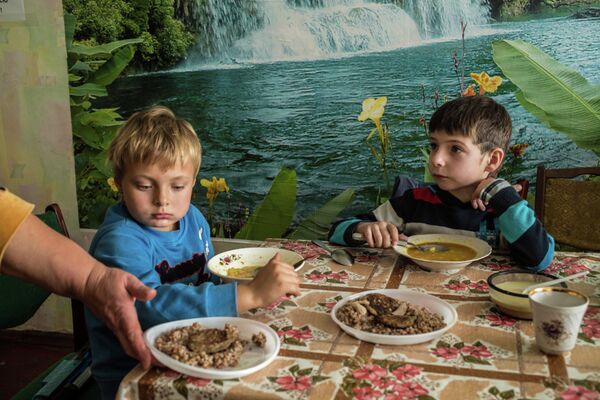 Владик и Максим обедают в благотворительной организации, осуществляющей помощь беженцам в Днепропетровске, Украина