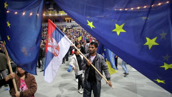Люди держат флаги Сербии и ЕС