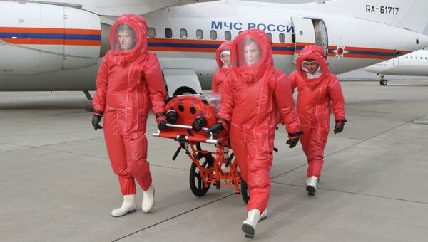 Сотрудники МЧС в защитных костюмах с изолирующими дыхательными аппаратами везут медицинский модуль для перевозки инфицированных лихорадкой Эбола. Архивное фото