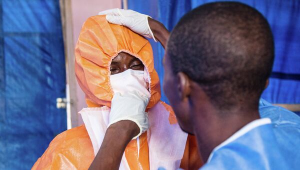 Медицинский работник надевает защитный костюм перед посещением зараженных вирусом Эбола. Архивное фото
