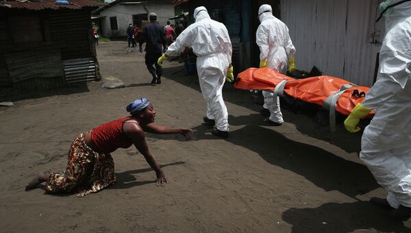 Члены команды захоронения несут тело женщины, умершей от Эболы