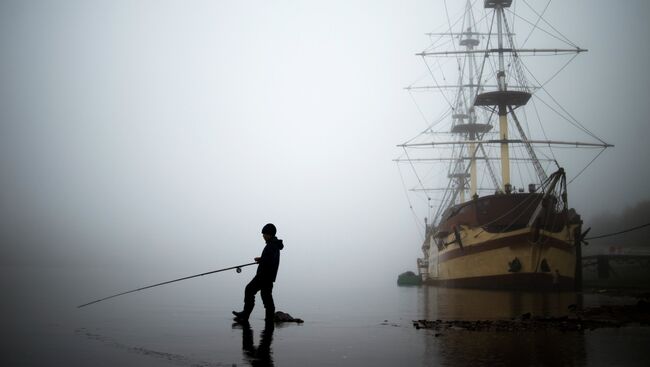 Мальчик ловит рыбу на фоне фрегата Флагман. Архивное фото