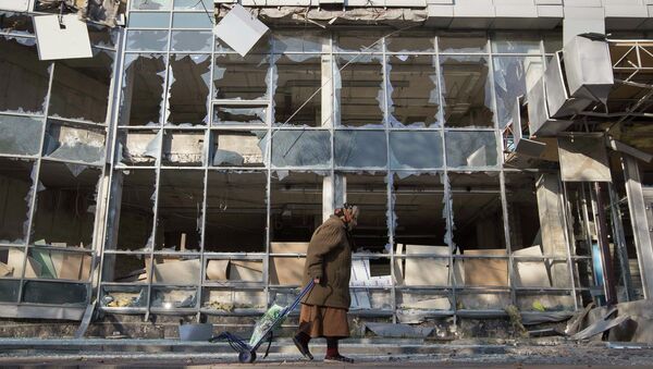 Женщина на фоне разрушенного в результате обстрела здания в Донецке, Украина. 15 октября 2014