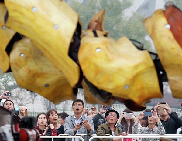 Зрители смотрят на механического дракона The Long Ma во время шоу в Пекине