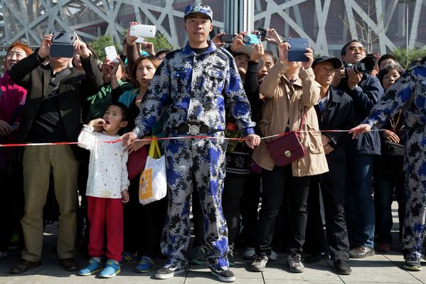 Сотрудник охраны и зрители во время шоу механических инсталляций в Пекине