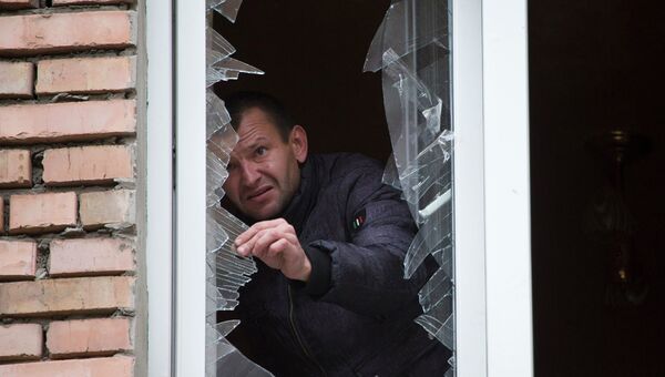 Мужчина убирает осколки от разбитого окна после обстрела Донецка 19 октября 2014