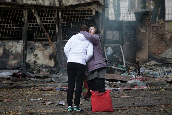 Жители Донецка на фоне повреждений города от обстрела в районе аэропорта